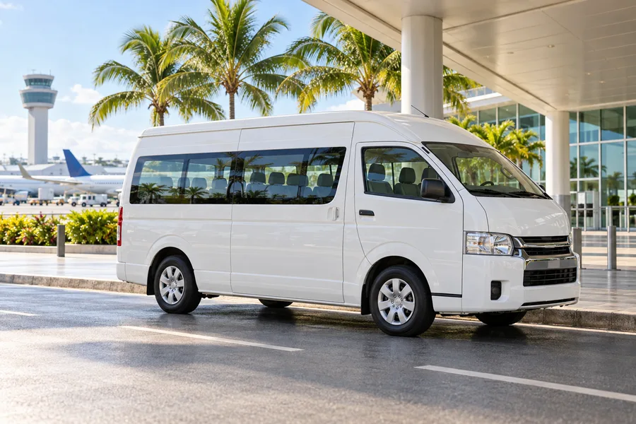 White airport shuttle bus at a tropical airport curb